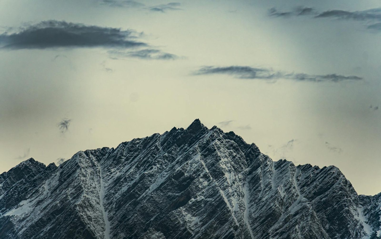 A snow-scored mountain ridge beneath a pale sky